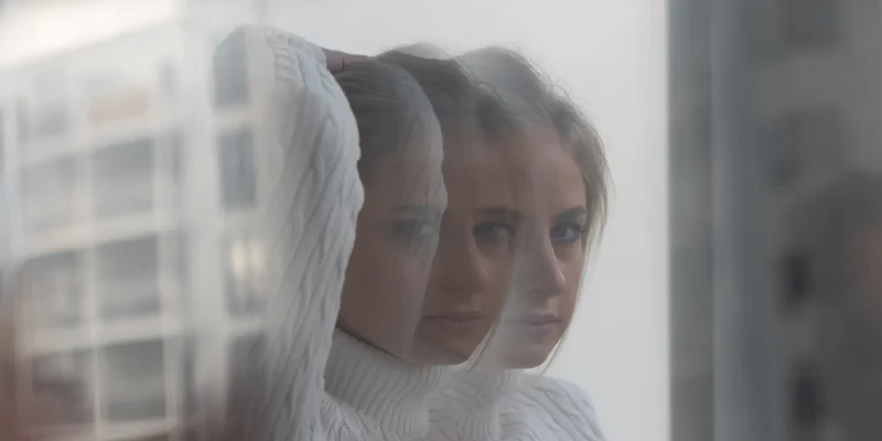 woman in white shirt looking out the window